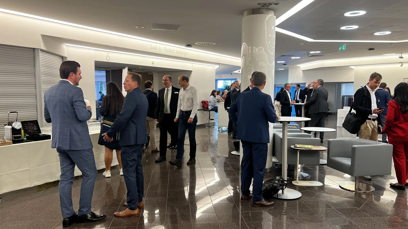 Industry participants in conversation around standing tables outside Saal 6 at WKO in Vienna.
